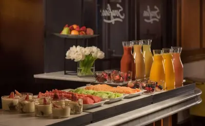 a buffet with plates of fruit and juice and drinks at NH Collection New York Madison Avenue in New York