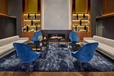 a living room with a fireplace and blue chairs at NH Collection New York Madison Avenue in New York