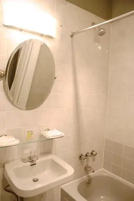 a bathroom with a sink and a tub and a mirror at Off SoHo Suites Hotel in New York