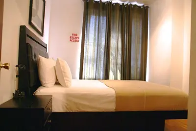 a bedroom with a bed with white sheets and a window at Off SoHo Suites Hotel in New York