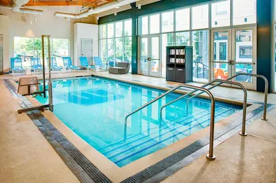 a large swimming pool with blue chairs in a building at Aloft Philadelphia Airport in Philadelphia
