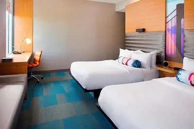 a hotel room with two beds and a desk at Aloft Philadelphia Airport in Philadelphia