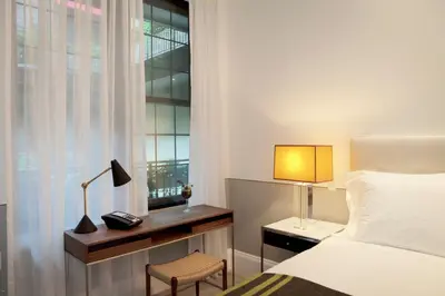a bedroom with a bed and a desk and a window at The Broome in New York