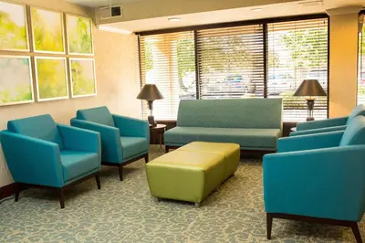a waiting room with blue and green chairs and windows at Days Inn by Wyndham Newark Wilmington in Newark