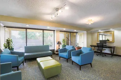a waiting room with blue chairs and a piano at Days Inn by Wyndham Newark Wilmington in Newark