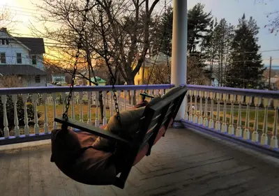 a person swinging in a hammock on a porch at CHARMING EXECUTIVE VICTORIAN MANSION w/ FREE PARKING - near Bucknell in Milton
