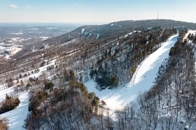 a snow covered hill with trees and a ski slope at Camelback 302 in Tannersville
