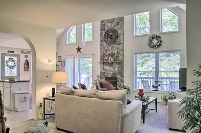 a living room with a couch and a stone fireplace at Spacious Home with Deck, Grill and Delaware River View in Callicoon