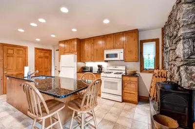 a kitchen with wooden cabinets and a table with chairs at Waterfront Highland Lake Home with Deck and Dock in Highland Lakes