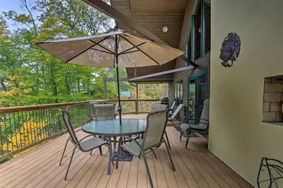 a patio with a table and chairs and an umbrella at Waterfront Highland Lake Home with Deck and Dock in Highland Lakes