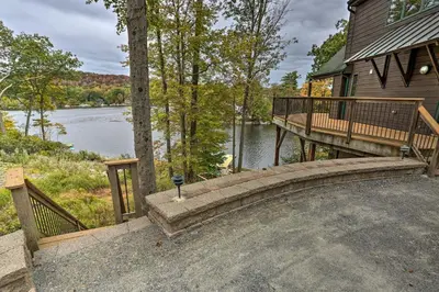 a house with a deck and a bench next to a lake at Waterfront Highland Lake Home with Deck and Dock in Highland Lakes