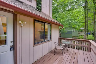 a wooden deck with a table and a chair on it at Deck and Fire Pit Pocono Lake Home Near Skiing! in Pocono Lake