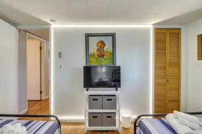 a room with two beds and a tv on a wall at Happy Place by the Lake with Fire Pit Walk to Beach in Pocono Lake