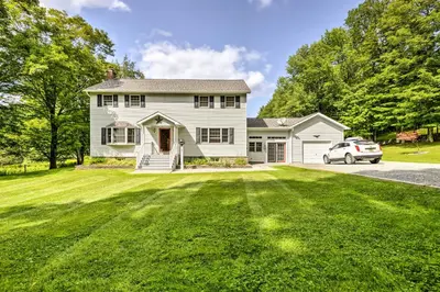 a white house with a car parked in a yard at Thompson Home with Deck and Pond, 8 Mi to Elk Mountain in Thompson
