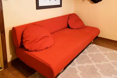 a red couch with two pillows sitting in a room at 180-Acre Farm The Lodge in Klingerstown! in Klingerstown