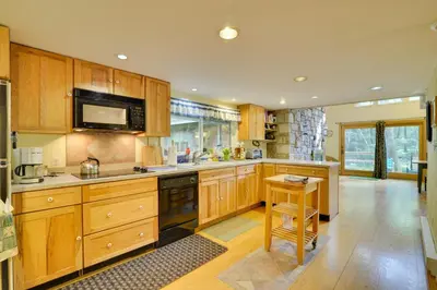 a large kitchen with wooden cabinets and a table at Secluded Stroudsburg Home - 5 Mi to Ski Resort in Stroudsburg