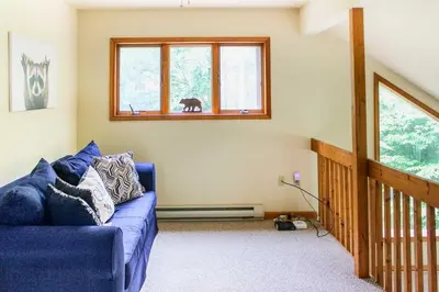 a living room with a blue couch and windows at Walk to Beach Beautiful Lake Naomi Retreat! in Pocono Pines