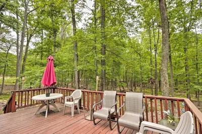 a wooden deck with chairs and a table and an umbrella at Relaxing Eagle Rock Resort Home - 1 Block to Lake! in Hazleton