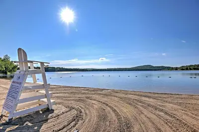 a lifeguard chair sitting on a beach near a body of water at Creekside Arrowhead Lake House with Dock and Canoe! in Pocono Lake
