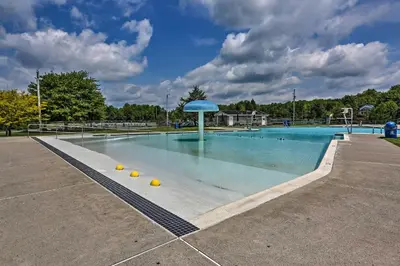 a large swimming pool with a blue umbrella in it at Creekside Arrowhead Lake House with Dock and Canoe! in Pocono Lake