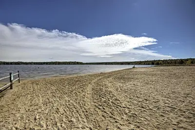 a sandy beach with a fence and a body of water at Pocono Retreat Access to Community Lake and Beach! in Albrightsville