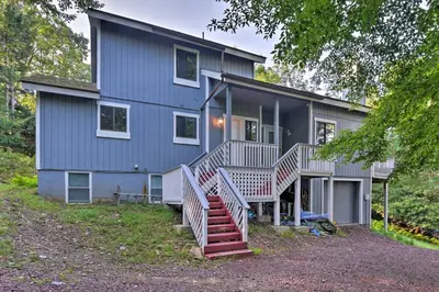 a blue house with stairs in front of it at Hot Tub and Fire Pit Waterfront Lake Harmony Home in Lake Harmony