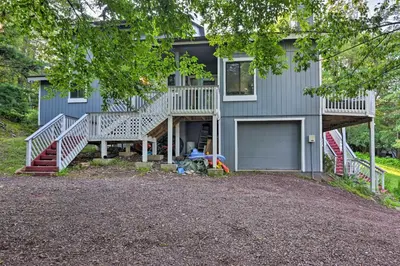 a blue house with a porch and a garage at Hot Tub and Fire Pit Waterfront Lake Harmony Home in Lake Harmony