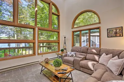 a living room with large windows and a couch at Pocono Lake Paradise with Private Beach and Dock! in Pocono Lake