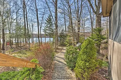 a walkway leading to a lake in the woods at Pocono Lake Paradise with Private Beach and Dock! in Pocono Lake