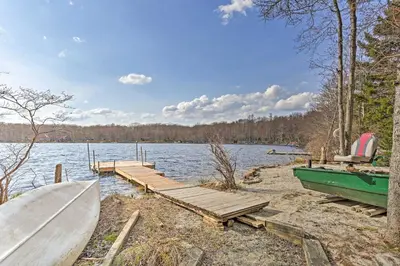a dock and a boat on the shore of a lake at Pocono Lake Paradise with Private Beach and Dock! in Pocono Lake