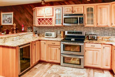 a kitchen with wooden cabinets and stainless steel appliances at Lake Harmony Vacation Rental with Hot Tub and Views! in Lake Harmony