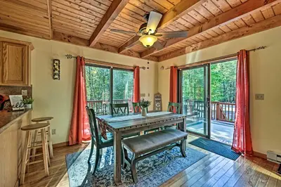 a kitchen and dining room with a wooden table and chairs at Mountain Cabin with Deck Near Year-Round Recreation! in Lake Ariel