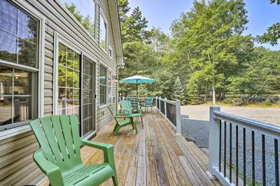 a porch with two chairs and an umbrella at Near Lake and Hiking Pocono Home with Hot Tub in Albrightsville