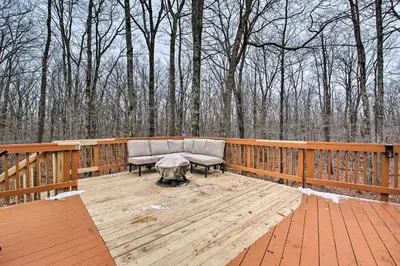 a couch sitting on a wooden deck with trees at Cozy Retreat with Deck and Hot Tub, 20 mins to Kalahari in Tobyhanna