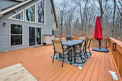 a deck with a table and chairs and an umbrella at Cozy Retreat with Deck and Hot Tub, 20 mins to Kalahari in Tobyhanna