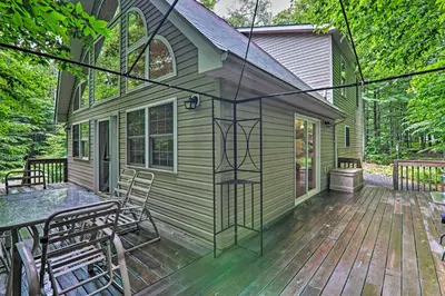a green house with a wooden deck with chairs at Deck and Resort Amenities Arrowhead Lake Home! in Pocono Lake