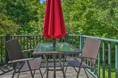 a table with a red umbrella on a deck at Mountain Creek Resort Home - Hot Tub and Pool Access in Vernon Township