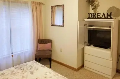 a bedroom with a dresser with a tv and a chair at Pocono Mountain Home with 3 Community Lakes! in Gouldsboro