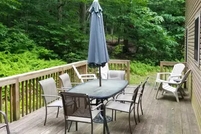 a table and chairs with an umbrella on a deck at Pocono Mountain Home with 3 Community Lakes! in Gouldsboro