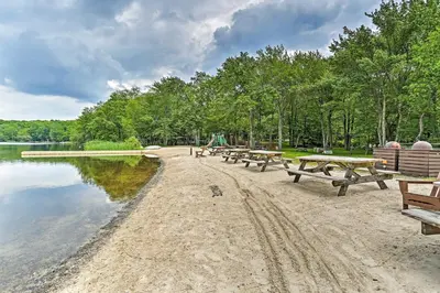 a row of picnic tables on the shore of a lake at Pocono Mountain Home with 3 Community Lakes! in Gouldsboro