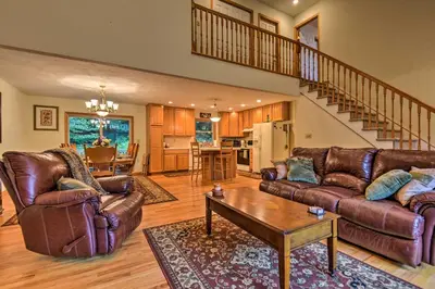 a living room with leather furniture and a staircase at Pocono Mountain Home with 3 Community Lakes! in Gouldsboro