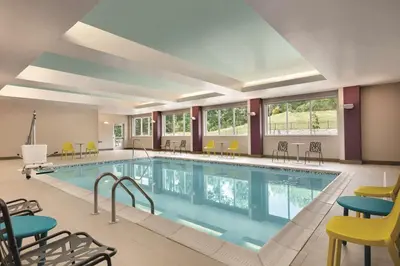 a pool in a hotel room with chairs and tables at Home2 Suites By Hilton Easton in Easton