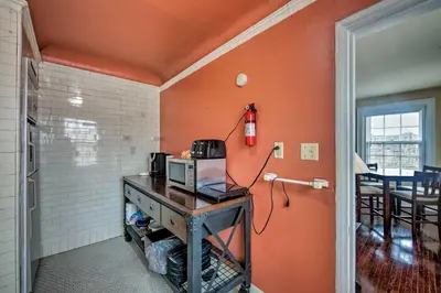 a room with orange walls and a table with a microwave at Walk to Shops, Dining and City Park Reading Apt in Reading
