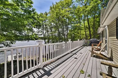 a wooden deck with a white fence next to a house at Waterfront Pocono Lake Home with Private Dock! in Pocono Lake