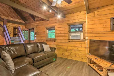 a living room with a leather couch and a big screen tv at Pocono Log Cabin Fireplace, Fire Pits and Amenities in Pocono Lake