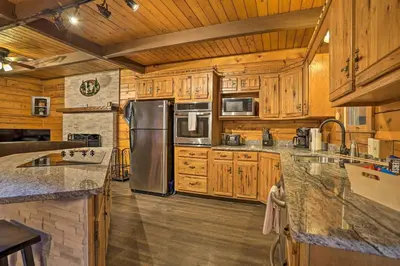 a kitchen with wooden cabinets and a stainless steel refrigerator at Pocono Log Cabin Fireplace, Fire Pits and Amenities in Pocono Lake