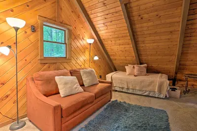 a living room with a couch and a bed in a cabin at Pocono Log Cabin Fireplace, Fire Pits and Amenities in Pocono Lake