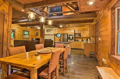 a dining room and kitchen with a wooden table and chairs at Pocono Log Cabin Fireplace, Fire Pits and Amenities in Pocono Lake