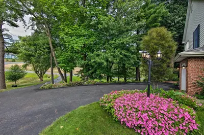 a driveway with pink flowers in front of a house at Charming Apartment with Yard and Beautiful Gardens! in Manheim