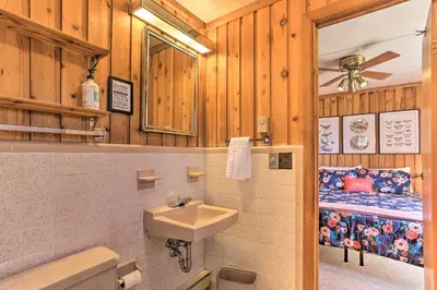 a bathroom with a sink and a toilet and a bed at Walk to Big Bass Lake Family Home with Deck! in Gouldsboro